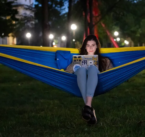 A UM student hanging out in a hammock at dusk.